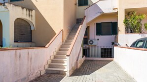 A narrow alleyway with a staircase leading to a building with a tiled floor and a metal gate. - Gandelli Holiday Home with Private Terrace, Wi-Fi and Air Conditioning (Orosei)