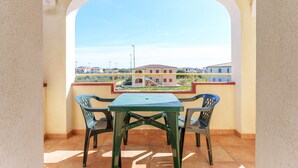 A balcony with a table and chairs, a view of buildings, and a clear sky. - Gandelli Holiday Home with Private Terrace, Wi-Fi and Air Conditioning (Orosei)