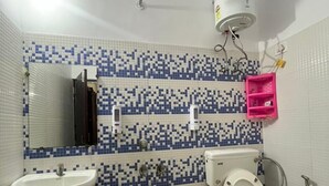 Un baño con inodoro, lavamanos, espejo y paredes de azulejos.
