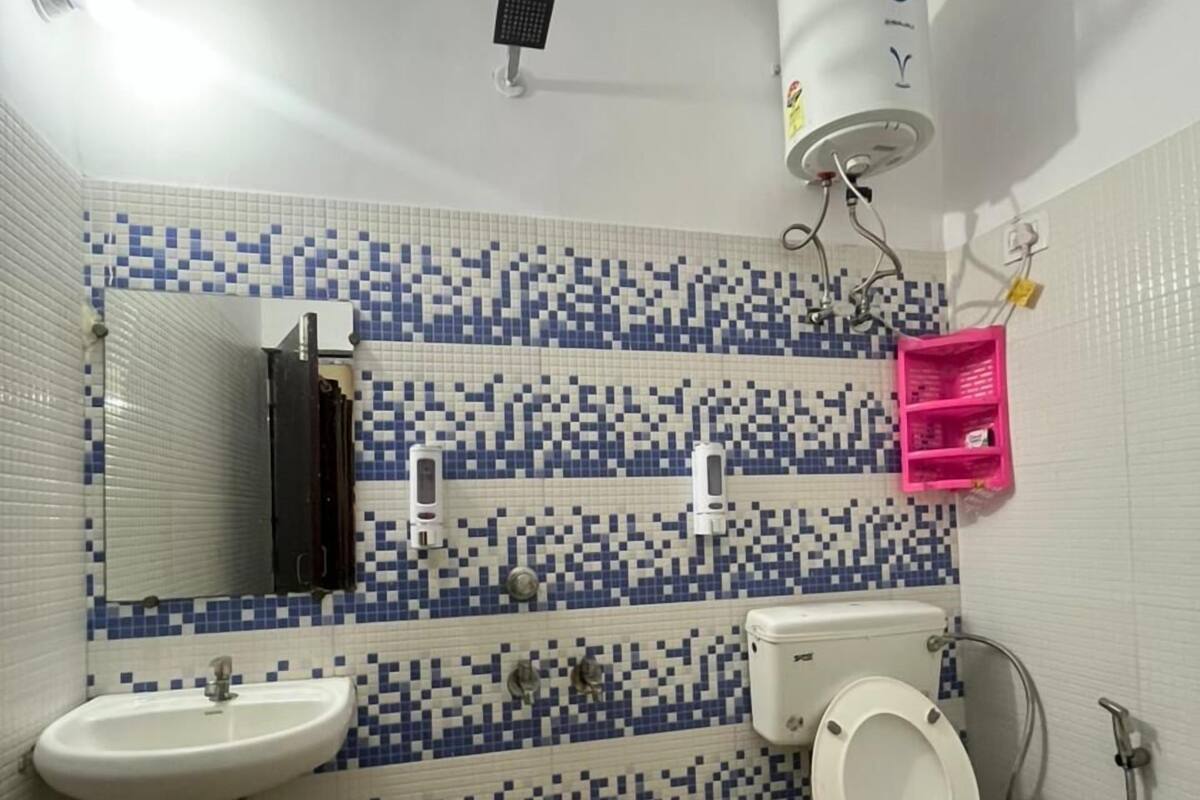 Un baño con inodoro, lavamanos, espejo y paredes de azulejos.