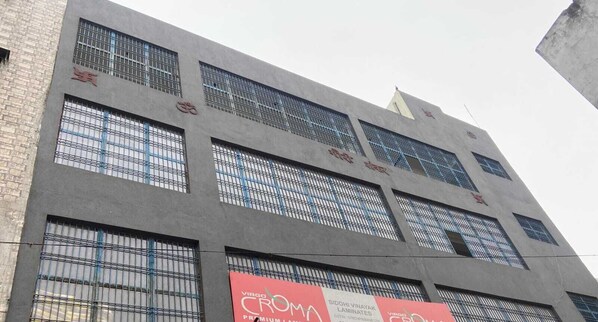 Un edificio con múltiples ventanas y un cartel anunciando VIRGO CROMA PREMIUM LAMINATES.