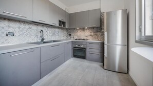 Een moderne keuken met grijze kastjes, een roestvrijstalen koelkast en een decoratieve spatwand.