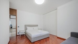 Een slaapkamer met een bed, nachtkastje, stoel en een kledingkast.