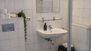 A modern bathroom with a toilet, sink, mirror, and shower. - Studio Zeeland - central location - kitchen - North Sea beach 25 min (Goes)