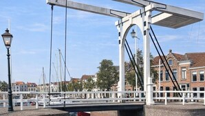 A canal with a wooden dock, a white bridge, and brick buildings in the background. - Studio Zeeland - central location - kitchen - North Sea beach 25 min (Goes)