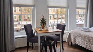 A hotel room with a bed, a small table with chairs, a Christmas tree, and large windows with blinds. - Studio Zeeland - central location - kitchen - North Sea beach 25 min (Goes)