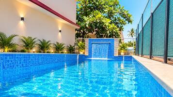 Una piscina con agua azul cristalina, rodeada por un muro blanco y un travesaño rojo.