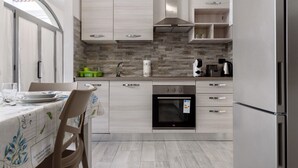Une cuisine moderne avec des meubles de couleur bois clair, un four encastré et un réfrigérateur en acier inoxydable.