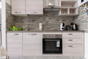 Une cuisine moderne avec des meubles de couleur bois clair, un four encastré et une hotte de cuisine en acier inoxydable.
