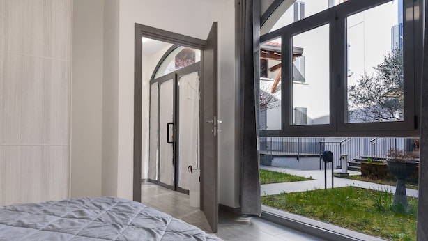Une chambre avec un grand lit, une porte-fenêtre coulissante donnant sur un balcon et une vue sur l’extérieur.