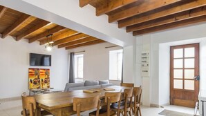 Ein geräumiges Zimmer mit einem Holzesstisch, Stühlen, einer Couch und einem Fernseher.