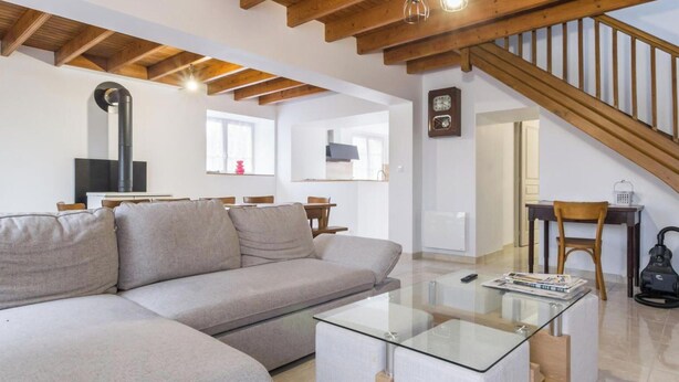 Ein Wohnzimmer mit einer Couch, einem Glastisch, einem Kamin und einer Treppe.