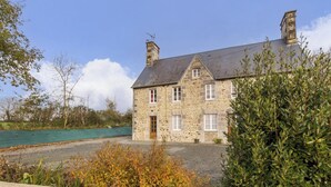 Ein Steinhaus mit geneigtem Dach, mehreren Schornsteinen und einer Haustür.