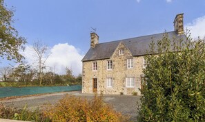 Ein Haus aus Stein mit einem geneigten Dach, einem Schornstein und einer kleinen Veranda.