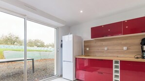 Eine moderne Küche mit einer Schiebeglastür, einem weißen Kühlschrank, roten Schränken und einer Holzausziehtafel.