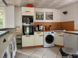 A compact kitchen with a microwave, oven, coffee maker, and a washing machine. - House near centre, parking - 10 guests (La Palmyre)