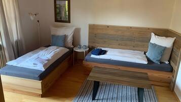 Una habitación con dos camas, una mesita, una lámpara y un cuadro en la pared.