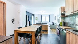 A modern kitchen with a wooden dining table, black chairs, and a built-in oven.