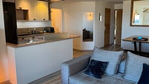 A modern kitchen with a central island, a dining area with a table and chairs, and a living space with a sofa and cushions. - Charming apartment, sea view - 4 guests (Cabourg)