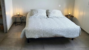 Un dormitorio con cama, dos mesitas de noche con lámparas y una puerta.