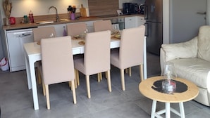 Una cocina moderna con armarios blancos, horno integrado y televisor de pantalla plana.