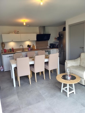 A modern kitchen with white cabinets, a built-in oven, and a flat-screen TV. - Seaside Gîte La Guichardière: Shared Terrace, Private Garden & Wi-Fi in Pirou (Pirou)