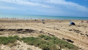 Una playa con gente, tiendas de campaña y un cielo despejado.