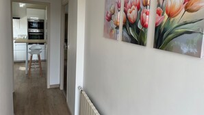 Ein Flur mit einer Küche im Hintergrund, einem Heizkörper und drei Tulpenbildern an der Wand.