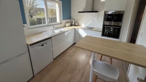 Eine moderne Küche mit Fenster, weißen Schränken, einer Holz Arbeitsplatte und einem eingebauten Backofen.