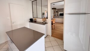 A modern kitchen with a large island, white cabinetry, and a mirror above the countertop. - House with enclosed garden and veranda (LES SABLES D'OLONNE)