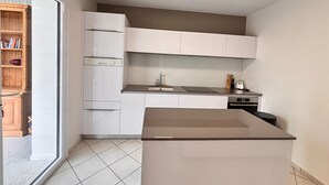 A modern kitchen with white cabinetry, a built-in oven, and a large window. - House with enclosed garden and veranda (LES SABLES D'OLONNE)