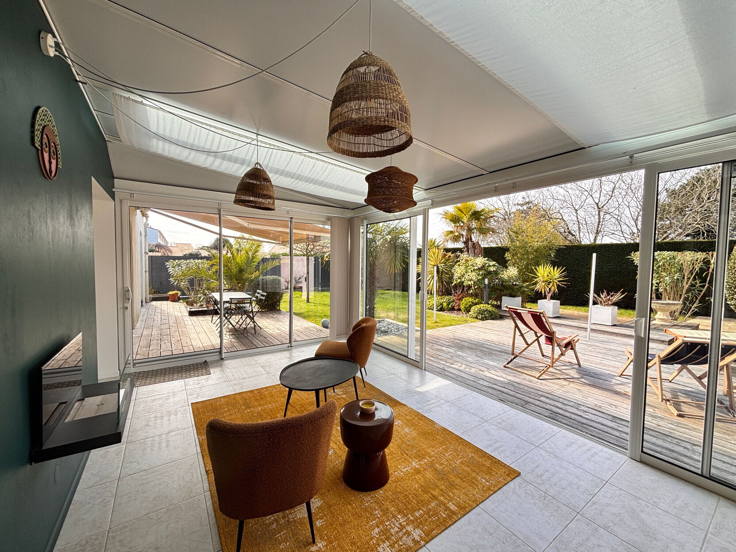 A modern interior with a glass door leading to a patio, a brown chair, a small table, and hanging wicker lamps.