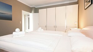 Ein Hotelzimmer mit einem großen Bett, einem Kleiderschrank, einem Nachttisch mit Lampe und einem Gemälde an der Wand.