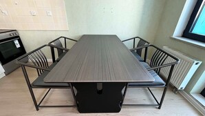 Un tavolo da pranzo rettangolare con base nera, circondato da quattro sedie nere con struttura in metallo.