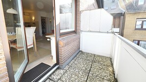 A balcony with a tiled floor, a glass door leading to an interior space, and a brick wall. - Ostdeich Stübchen vacation apartment: Balcony & beach nearby (Büsum)