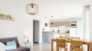 Una cocina moderna con armarios blancos, una mesa de comedor con sillas y una lámpara colgante.