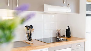 Una cocina moderna con gabinetes blancos, una placa de inducción negra y una cafetera.