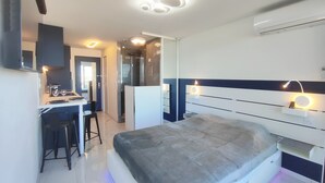 A modern bedroom with a bed, a desk, and a shower. - Studio with AC, sea view - 2 guests (Le CAP D'AGDE)