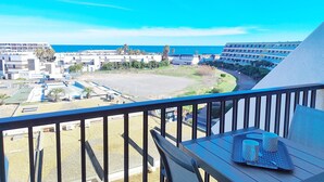 A balcony with a table, chairs, and a tray with cups and a spoon. - Studio with AC, sea view - 2 guests (Le CAP D'AGDE)