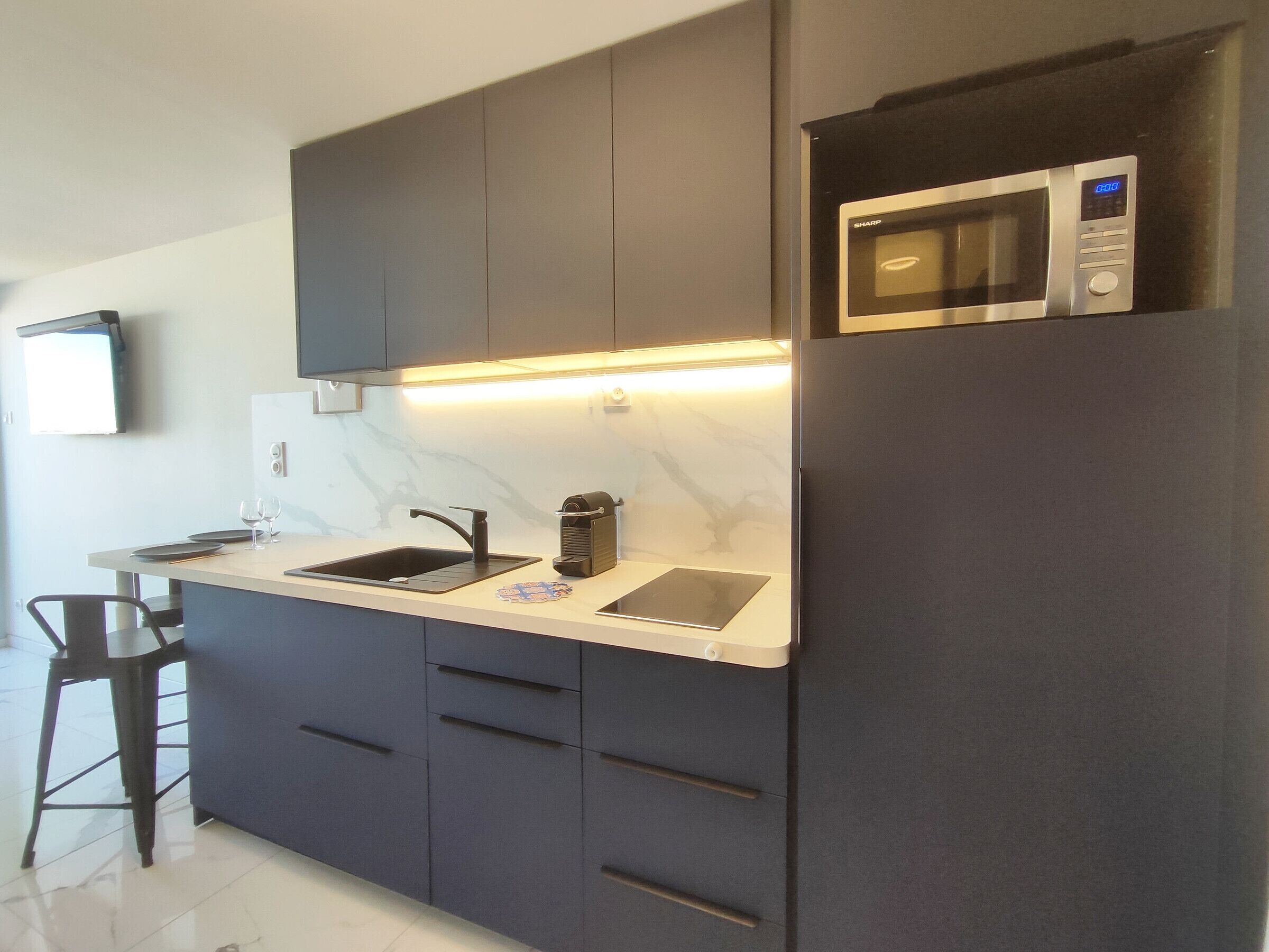 A modern kitchen with a built-in microwave, a sink, and a coffee machine.