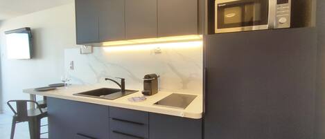 A modern kitchen with a built-in microwave, a sink, and a coffee machine.