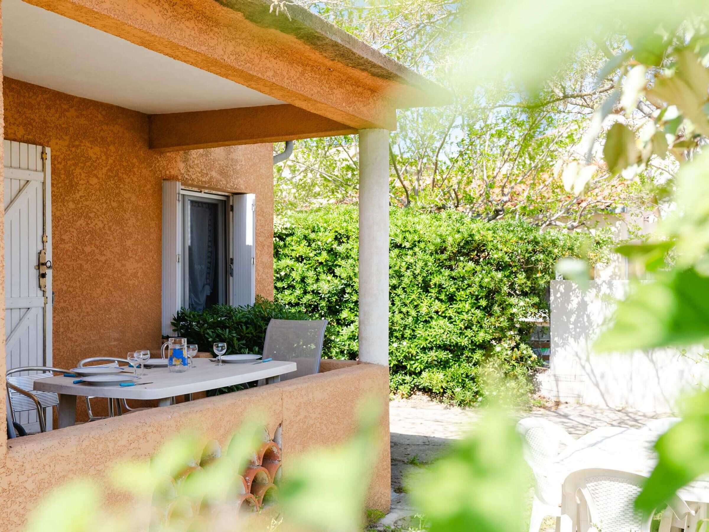 An outdoor patio with a table, chairs, and a door.