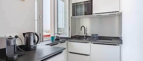 Una cocina moderna con microondas integrado, hervidor y cafetera sobre la encimera.