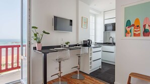 Eine moderne Küche mit Fernseher, Barhocker und Blick auf den Strand.