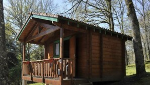 A wooden cabin with a balcony, a door, and a staircase leading up to it.