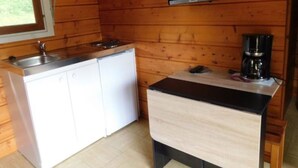 A compact kitchen with a microwave, a small refrigerator, a coffee maker, and a television mounted on the wall.