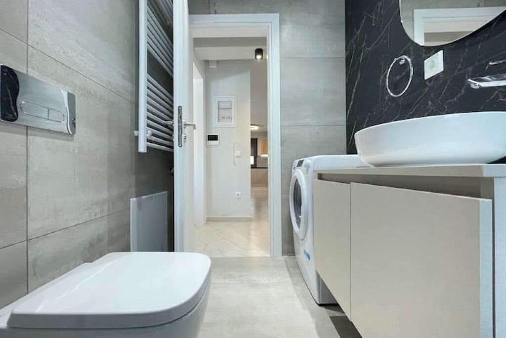 Ein modernes Badezimmer mit Toilette, Waschmaschine und Waschbecken.