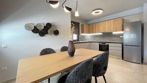Eine moderne Küche mit Edelstahlgeräten, einem Holztisch und grau gepolsterten Stühlen.