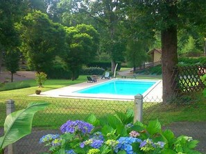 A rectangular swimming pool surrounded by a chain-link fence, with a lawn and trees in the background. - Family Mobile Home 4 Pers with Terrace (Rochechouart)