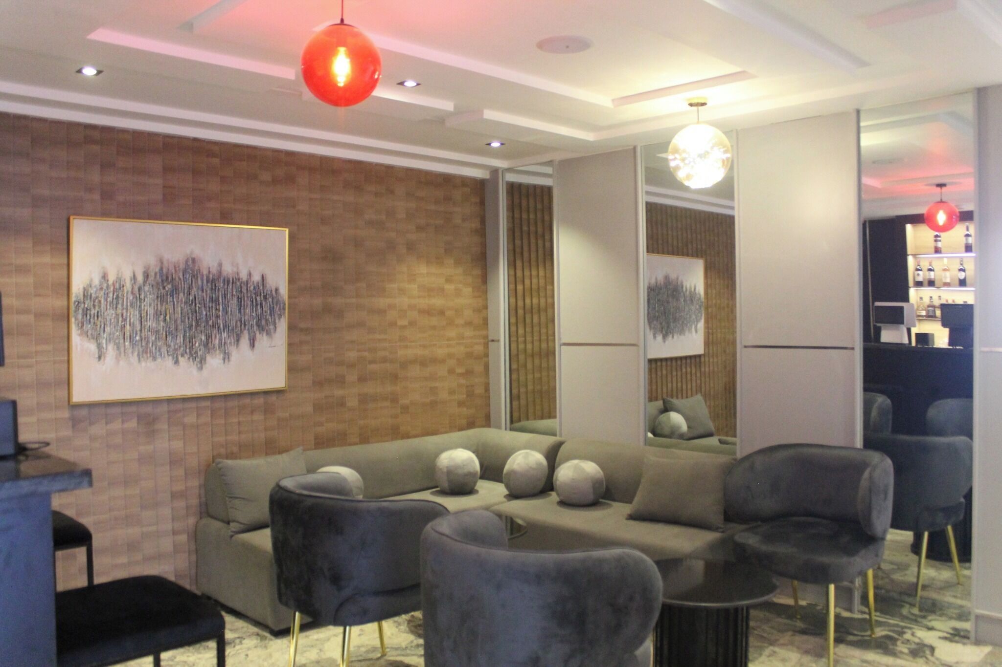 A modern living room with a sectional sofa, armchairs, a coffee table, and a red pendant light.